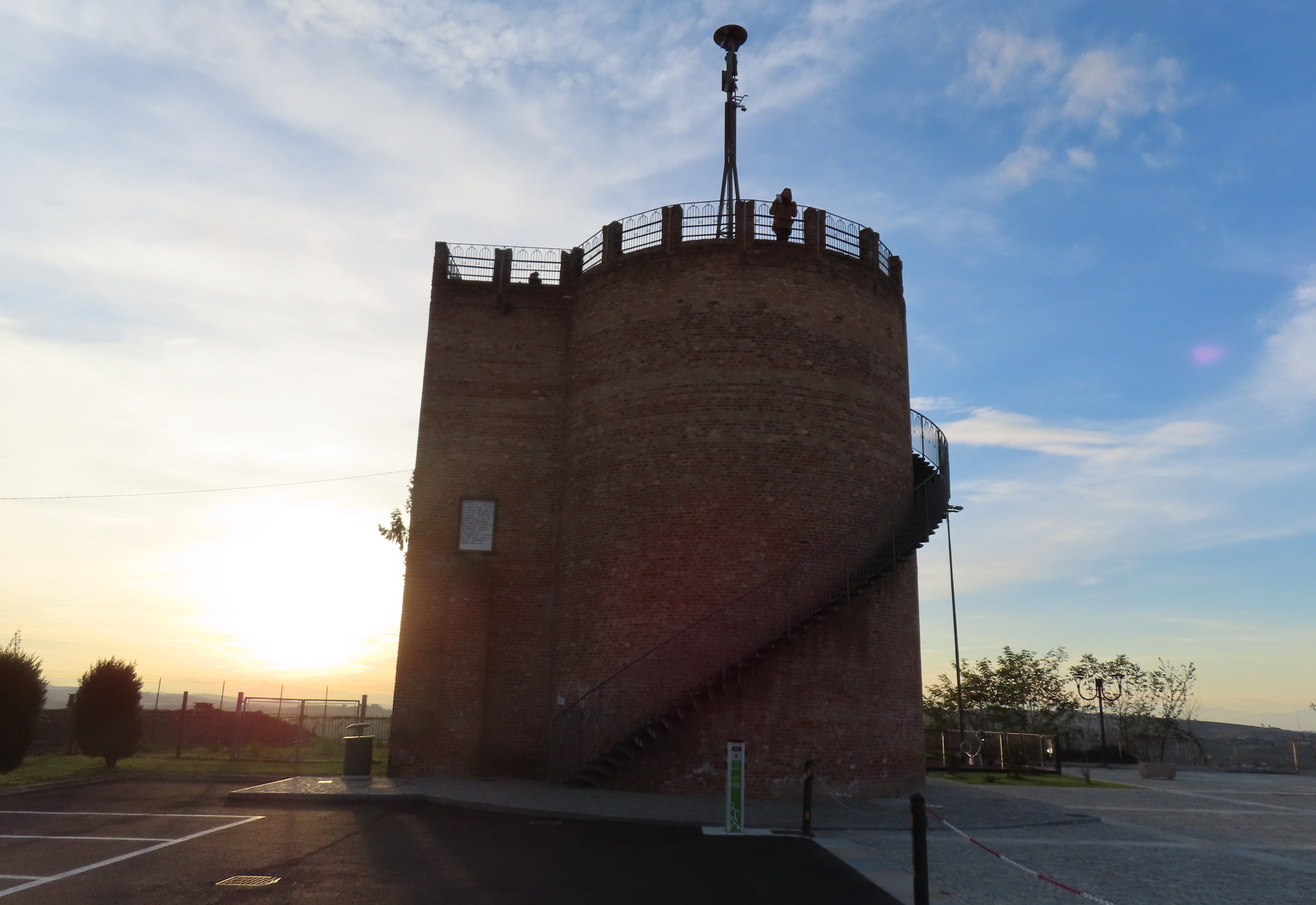The brick panoramic tower of Agliano Terme at sunset, with its external spiral staircase