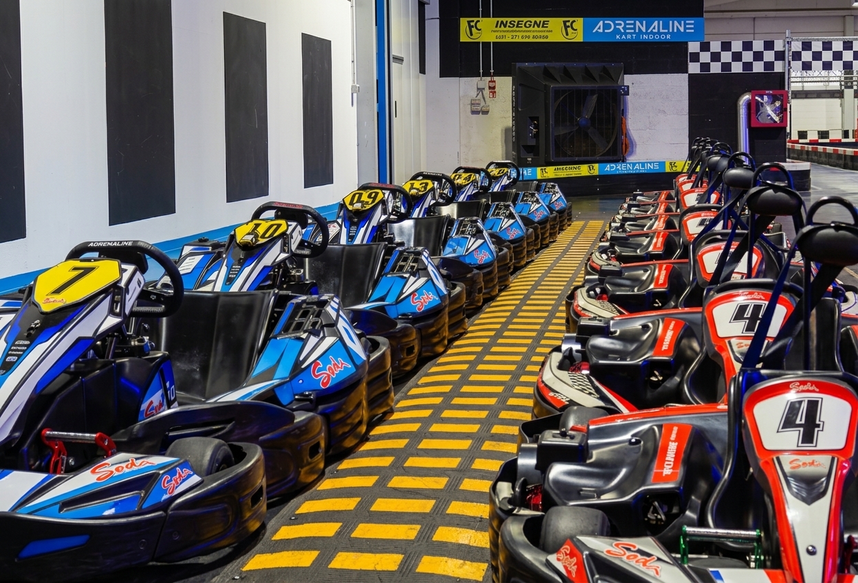 Karts lined up in the pit lane of the Adrenaline Kart Indoor track in Asti