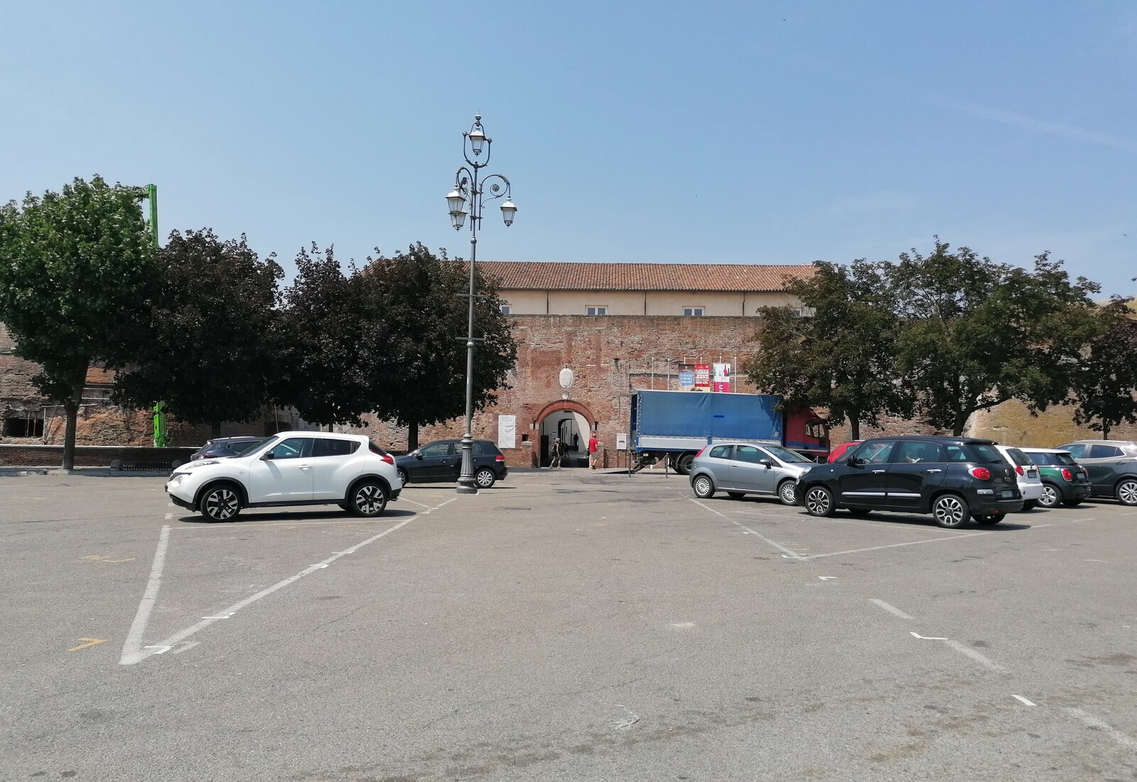 The brick gatehouse and walls of the Castello del Monferrato (Castello dei Paleologi) across its piazza
