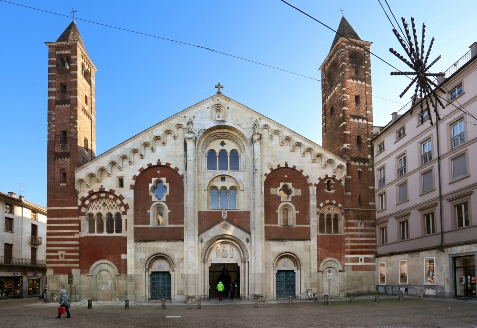 The Romanesque brick-and-stone facade of the Cattedrale di Sant'Evasio (Duomo) with its twin towers
