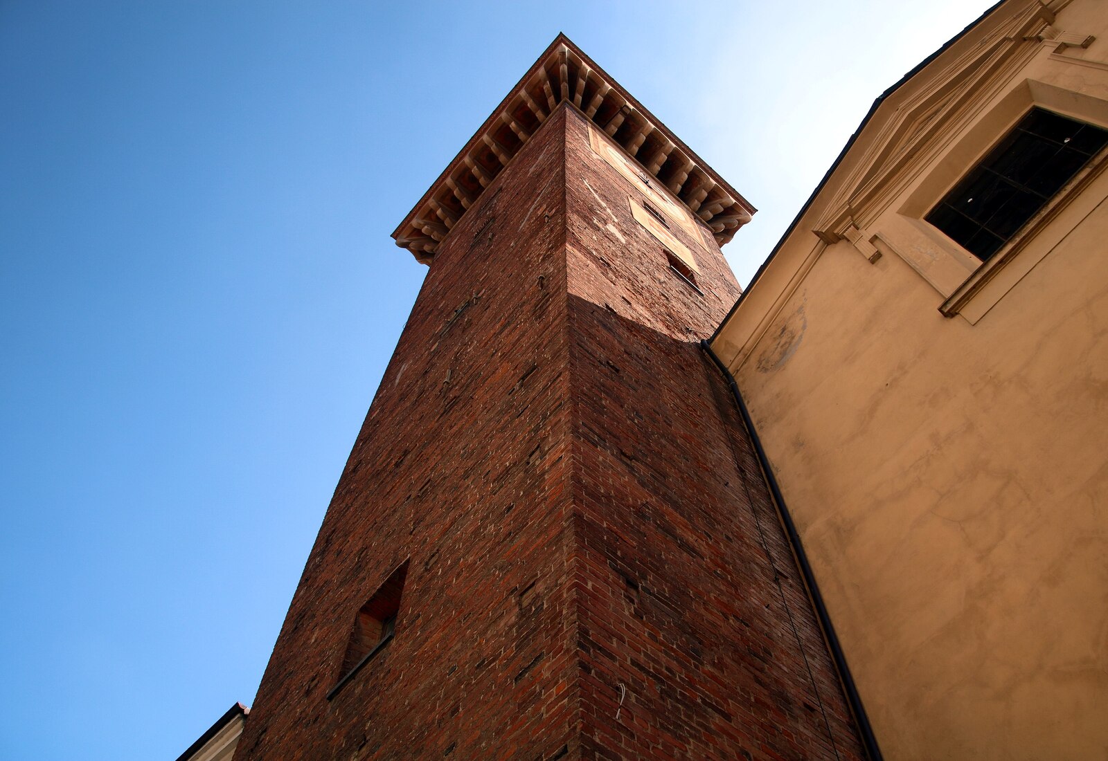 The medieval brick Torre Civica of Casale Monferrato seen from below against a blue sky