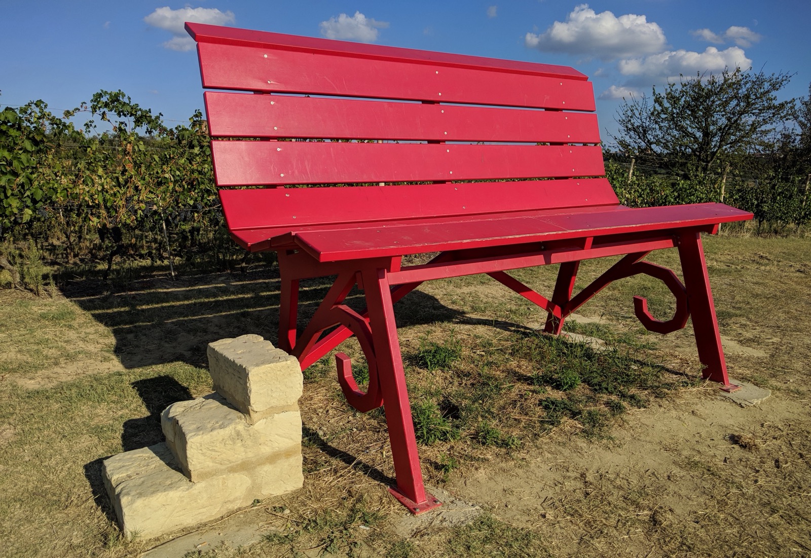 The red Big Bench of Grazzano Badoglio set among the vineyards under a blue sky