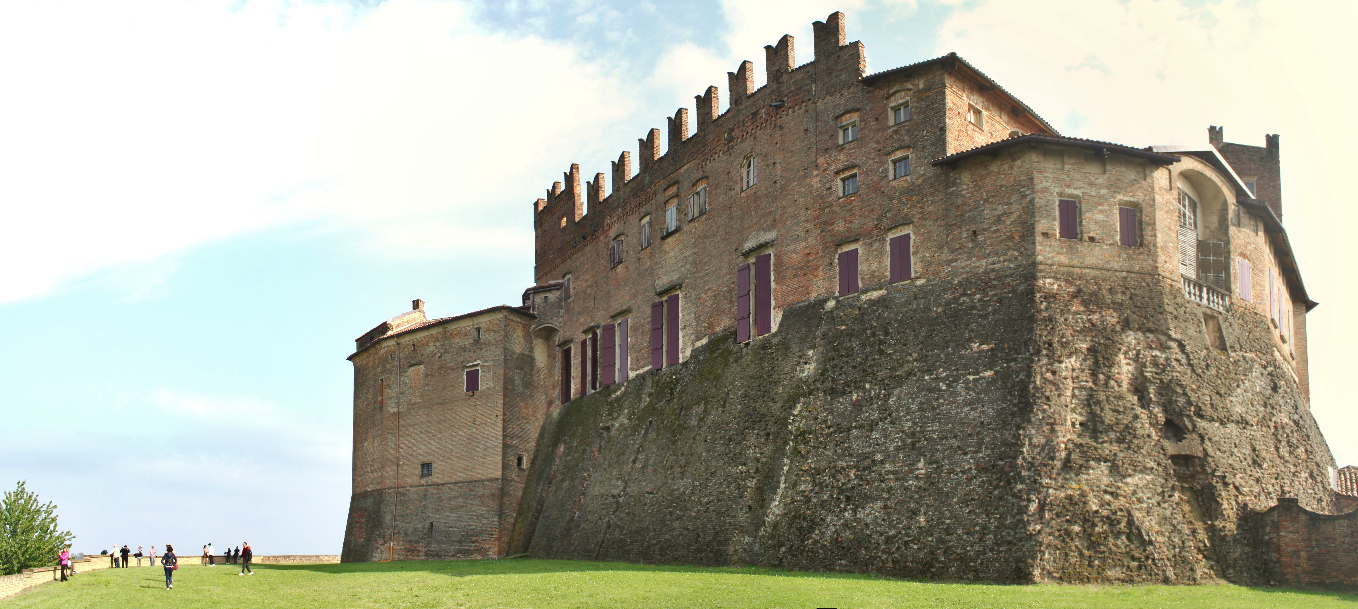 The Castello di Montemagno with its crenellated walls rising from a rocky base above a green lawn