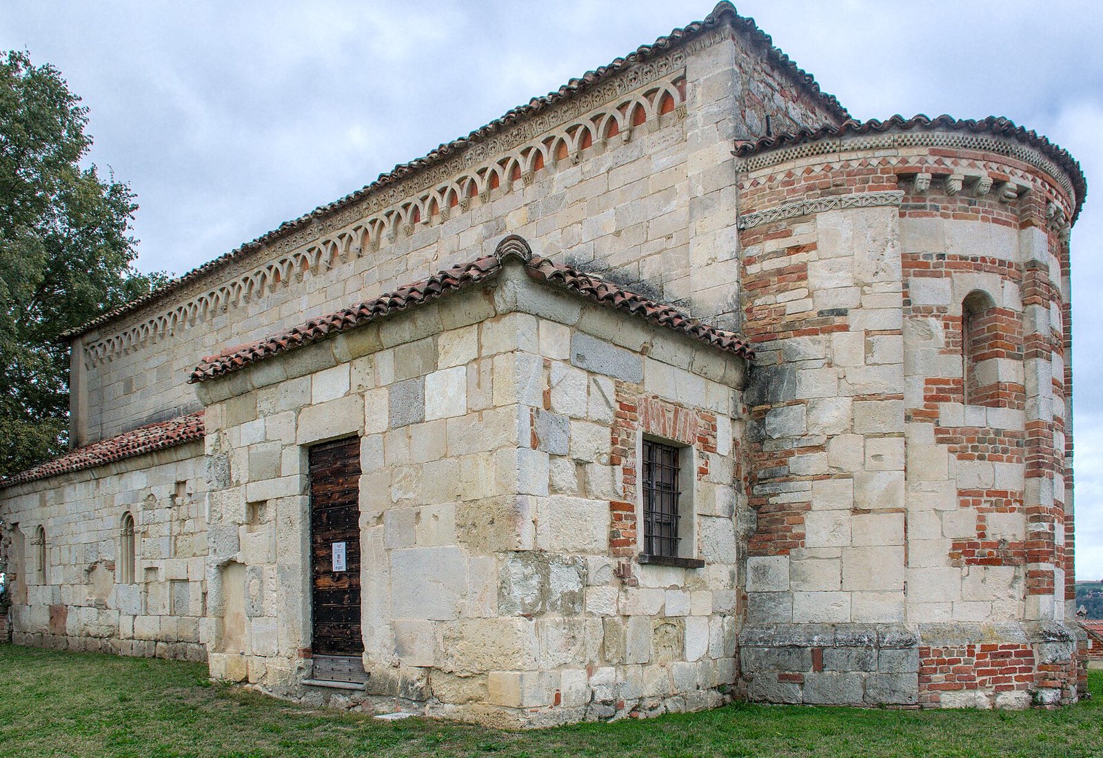 The 12th-century Pieve di San Lorenzo in pale sandstone, its apse banded with red brick and its eaves lined with carved hanging arches