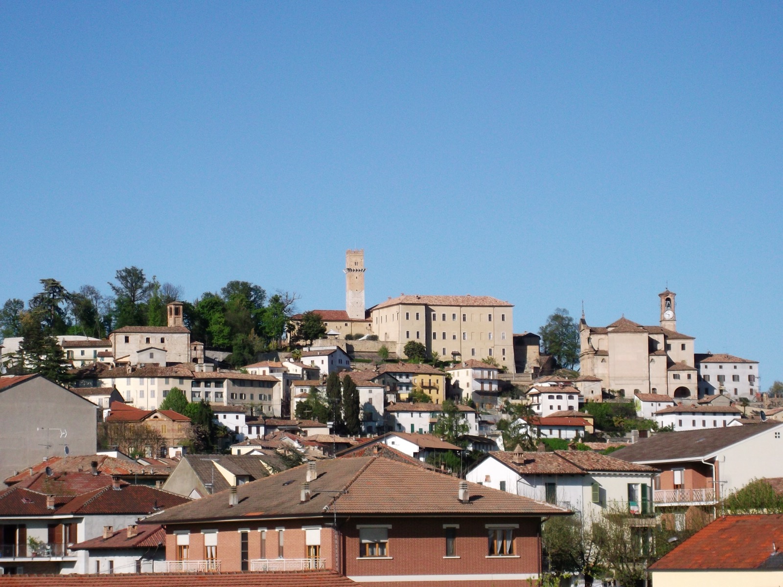 Murisengo on its hill, the castle and its tall tower crowning the old town centre under a blue sky