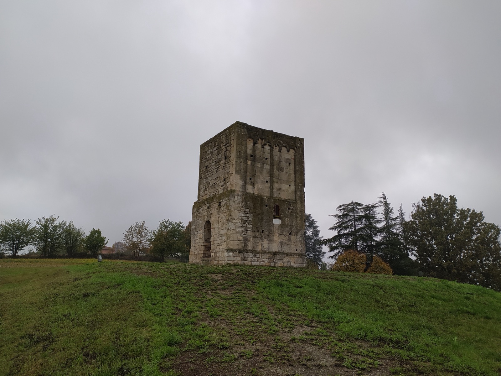 The Romanesque stone tower of San Pietro standing alone on a grassy hilltop above Murisengo