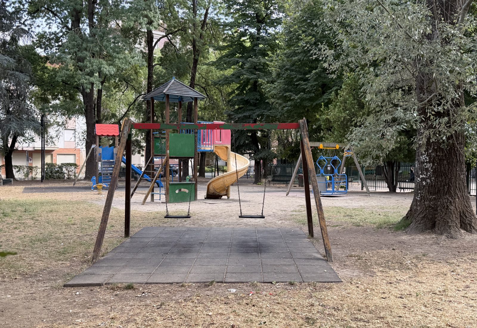 Swings and play structures under the trees at Parco Giovanni Paolo II