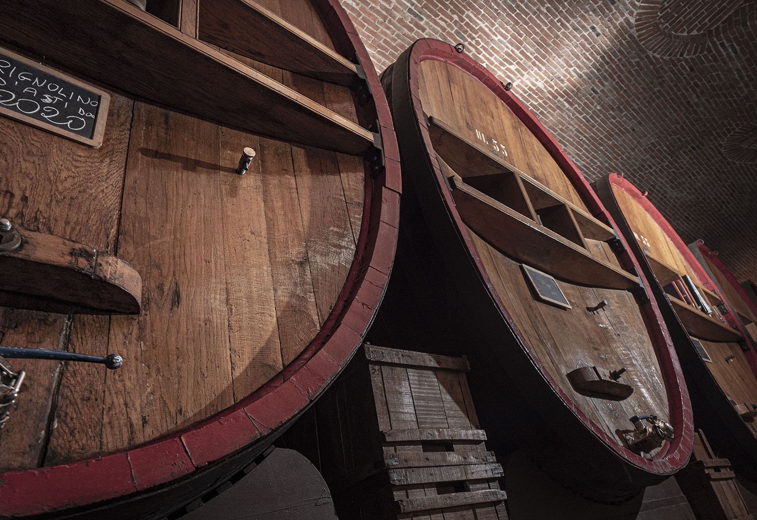 Large old oak casks lined up under the brick vault of the Caldera family's historic cellar