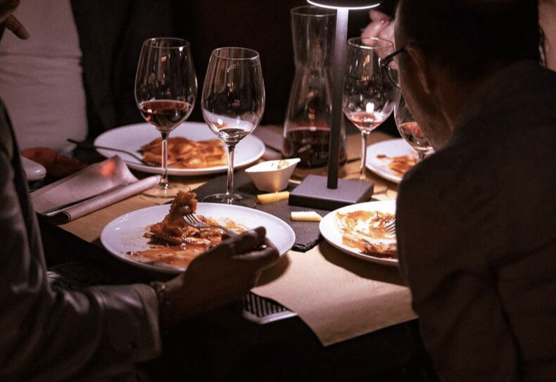 Glasses of red wine and plates on a lamp-lit table during an evening at Tenuta Il Capitolo